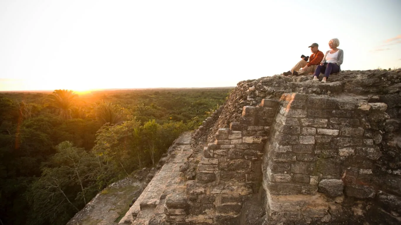 couple watching sunset from top of lamanai orange walk in belize