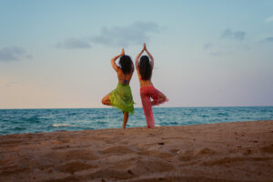Women doing yoga poses at the beach
