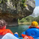 Cave-Tubing.Com - Tourists enjoying a guided cave tubing adventure on a river through lush jungle caves in Belize